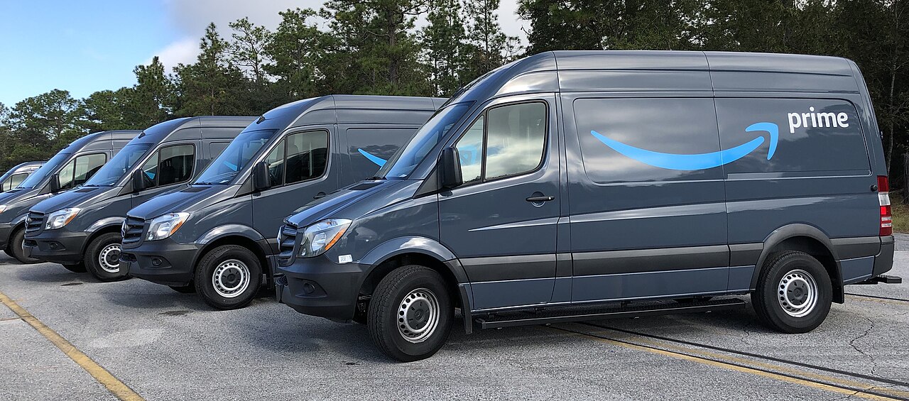 A row of gray Amazon Prime delivery vans parked outdoors in Gainesville, Florida, in 2018.