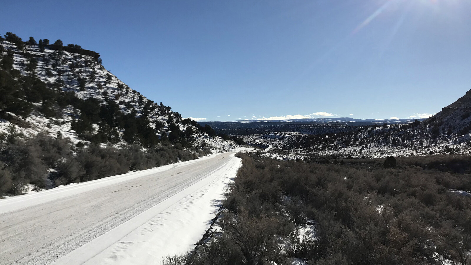 Snow-covered Wells Draw Road winding between rocky slopes in Gate Canyon, Utah