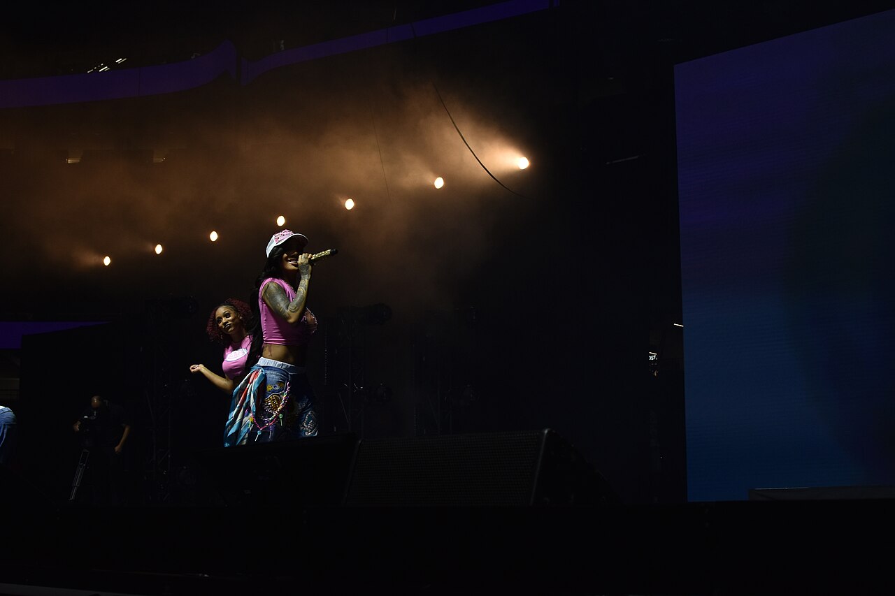 GloRilla performing onstage in a pink top and baseball cap at the 2025 Essence Festival of Culture.