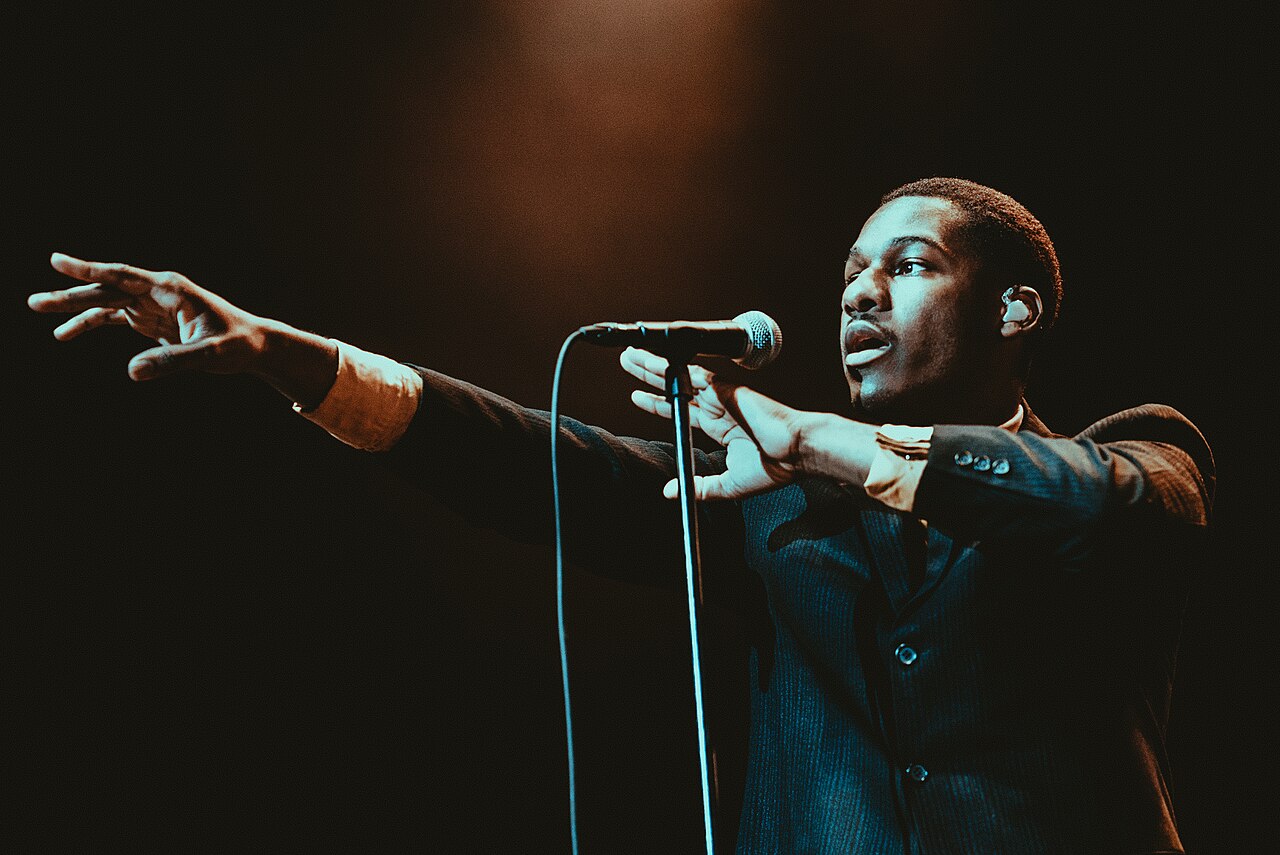 Leon Bridges singing into a microphone at Music Hall at Fair Park in Dallas