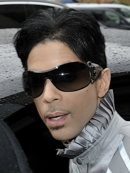 Prince wearing dark sunglasses and a gray ruffled collar at a Paris fashion event in 2009